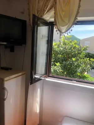 a window with a view of a green tree at Apartmani Centar in Petrovac na Moru