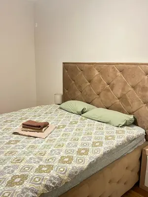 a bed with a headboard and a towel on it at Apartment Central point in Podgorica