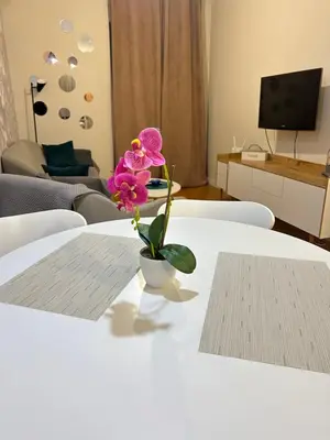 a pink flower in a white vase on a table at Apartment Central point in Podgorica
