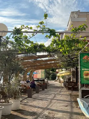 a walkway with trees and people sitting at tables at Step to the sea apartment in Rafailovici