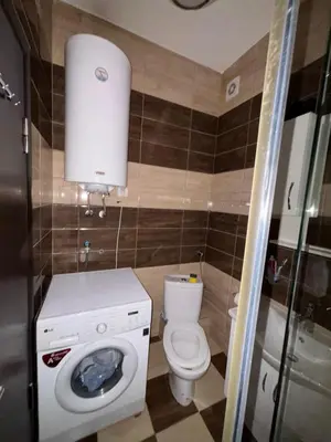 a small bathroom with a toilet and a washing machine at Enjoy 1 Apartmani in Podgorica
