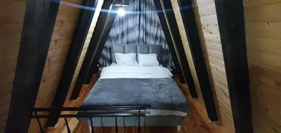 a bed in a wooden room with a black frame at Cozzy LUX apartment near the Airport Podgorica in Lajkovići