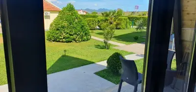 a view of a yard from a window with a chair at Cozzy LUX apartment near the Airport Podgorica in Lajkovići