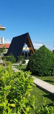 a building with a black roof and some bushes at Cozzy LUX apartment near the Airport Podgorica in Lajkovići