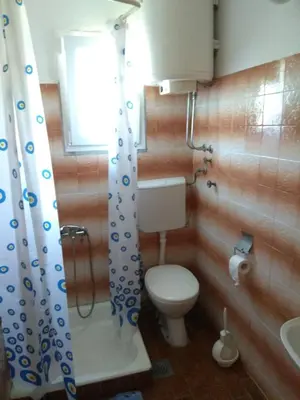 a bathroom with a toilet and a sink and a window at Apartment M2 Pine tree Sutomore in Sutomore