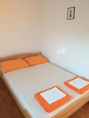 a bed with two orange pillows on it at Apartment M2 Pine tree Sutomore in Sutomore