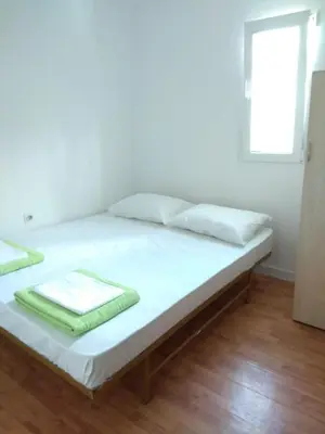 a bed with white sheets and a window in a room at Apartment M2 Pine tree Sutomore in Sutomore