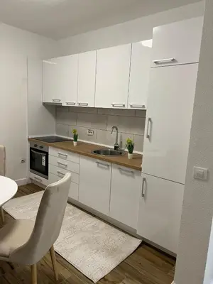 a kitchen with white cabinets and a sink and a chair at Villa House Ilda in Bar