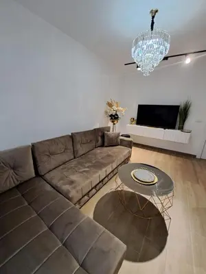 a living room with a brown couch and a chandelier at Apartments Pepdjonovic in Ulcinj