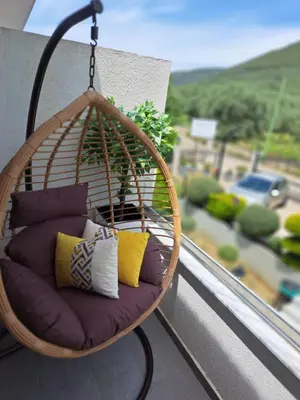 a hanging chair with pillows on a balcony at Apartments Pepdjonovic in Ulcinj