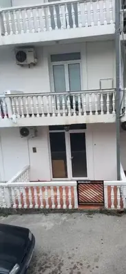 a white house with a balcony and a car parked in front at Apartment Sveti Stefan in Sveti Stefan