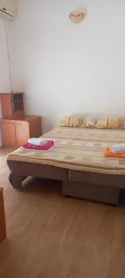 a large bed in a room with wooden floors at Apartman Olgica in Sutomore