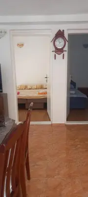 a room with a table and a clock on the wall at Apartman Olgica in Sutomore