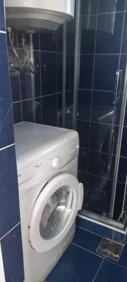 a washing machine in a bathroom with a blue tiled wall at Apartman Olgica in Sutomore