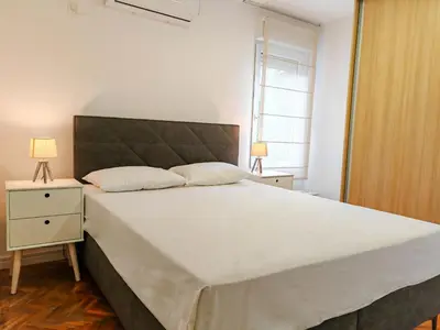 a bedroom with a large white bed with a night stand at Apartman Petar-Spacious Friendly Stay in the Heart of Budva in Budva