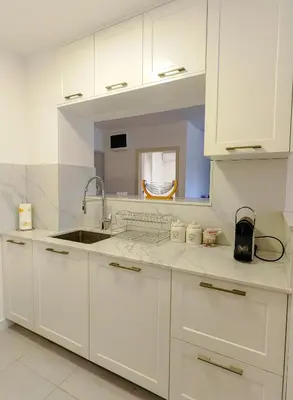 a kitchen with white cabinets and a sink and a mirror at Apartman Petar-Spacious Friendly Stay in the Heart of Budva in Budva