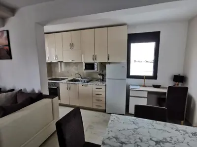 a kitchen with white cabinets and a table and a couch at Ulcinj Vibes & Waves Apartment in Ulcinj