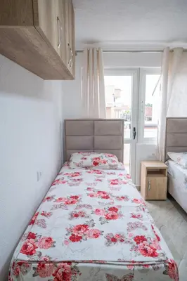 a bedroom with a bed with red flowers on it at Apartments Hamburg in Donji Štoj