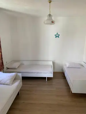 two beds in a room with white walls and wooden floors at Domaćinstvo Kvaić in Bar