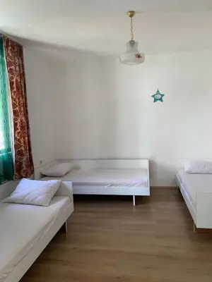 two beds in a room with white walls and wooden floors at Domaćinstvo Kvaić in Bar