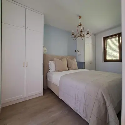 a white bedroom with a bed and a chandelier at Apartment Shell in Budva