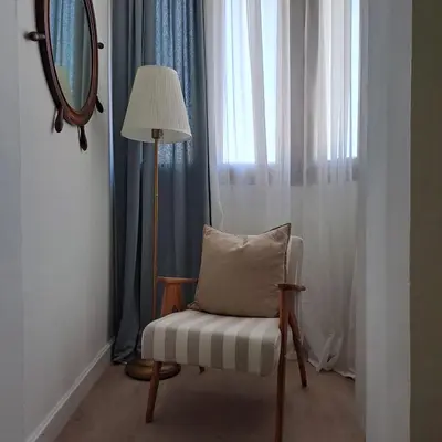 a chair with a pillow sitting next to a window at Apartment Shell in Budva