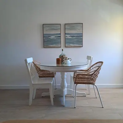 a white dining room table and chairs with two pictures at Apartment Shell in Budva