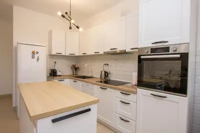 a kitchen with white cabinets and a wooden counter top at Oliva home in Utjeha