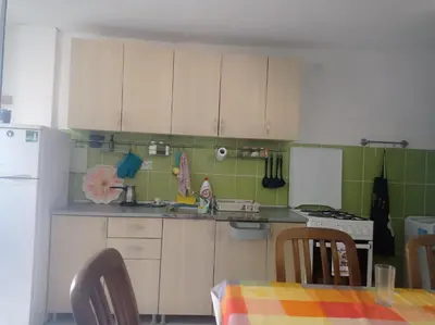 a kitchen with white cabinets and a table with chairs at Apartman Rogonjić in Sutomore