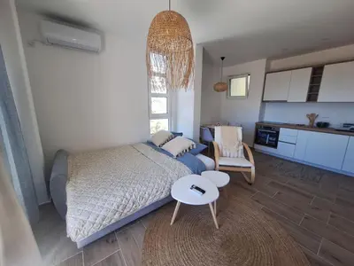 a bedroom with a bed and a table and a kitchen at Larimar Cozy Apartment in Ulcinj