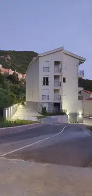 a white building with a parking lot in front of it at Inspired by Nature in Podličak
