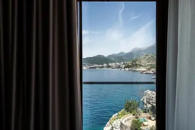 a window with a view of a body of water at Blanche Cliff Apartments in Sveti Stefan