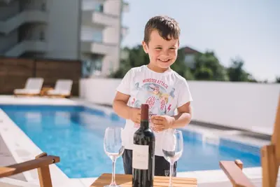 a young boy standing next to a bottle of wine at Belvedere Apartments in Ulcinj