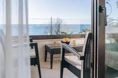 a table and chairs on a balcony with a view of the ocean at Apartments Kuce Lekovica Beach & snack bar- Bistro in Bar