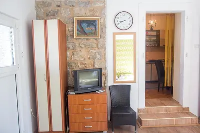 a tv sitting on a dresser next to a wall with a clock at Apartments Old Town in Budva