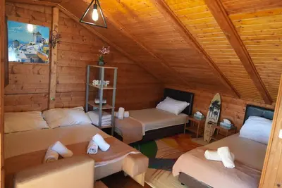a room with two beds in a wooden cabin at Ada Dream House in Kravlja