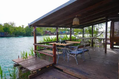 a wooden deck with a hammock and a table and chairs at Ada Dream House in Kravlja