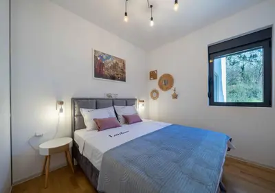 a bedroom with a large bed and a window at Maxim24 in Dobrota