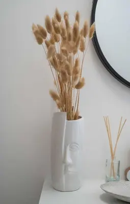 a white vase with some dried plants in it at Maxim24 in Dobrota