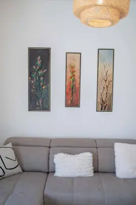 a living room with a couch and three paintings on the wall at Maxim24 in Dobrota