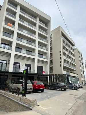 a parking lot with cars parked in front of a building at Stan Pinjes - Ulcinj in Ulcinj