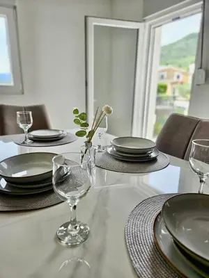 a white table with plates and glasses on it at V&L Apartman in Kravlja