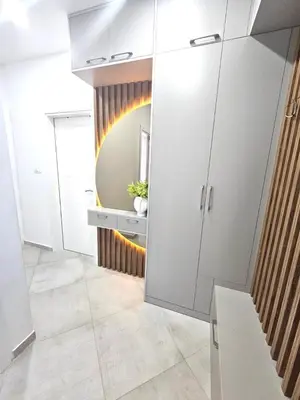 a bathroom with white cabinets and a mirror at V&L Apartman in Kravlja