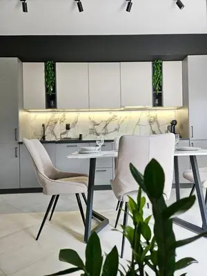 a kitchen with white cabinets and a table and chairs at V&L Apartman in Kravlja