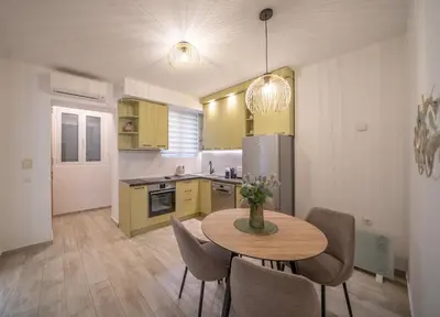 a kitchen with a table and chairs and a kitchen with yellow cabinets at Martin di Cattaro-Cosy Retreat Steps from Old Town in Kotor