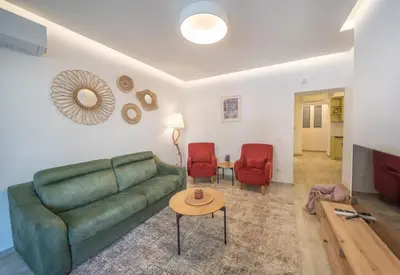 a living room with a green couch and two red chairs at Martin di Cattaro-Cosy Retreat Steps from Old Town in Kotor