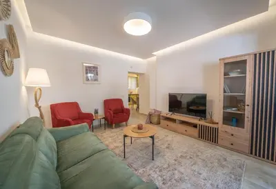 a living room with a green couch and red chairs at Martin di Cattaro-Cosy Retreat Steps from Old Town in Kotor
