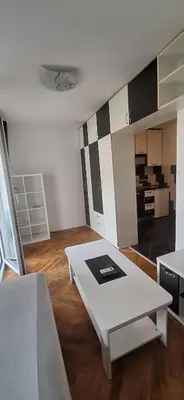 a living room with a white table and a kitchen at Apartman Budva in Budva