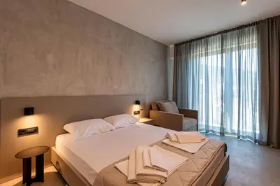 a bedroom with a bed and a chair and a large window at Lucciola Boutique Rooms in Budva