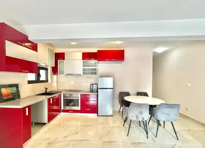 a kitchen with red cabinets and a table and chairs at Two bedroom apartment Andrej in Budva